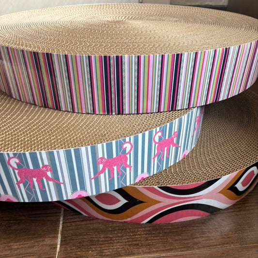 Three-tiered cat scratcher with colorful striped and patterned design on a wooden floor.